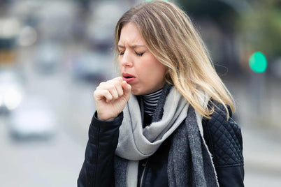 A woman coughing into her hand