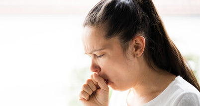 A woman coughing into her hand