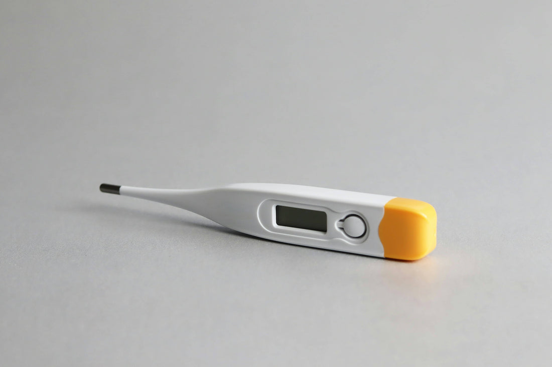 A digital thermometer resting on a gray surface, highlighting its modern appearance and functionality.
