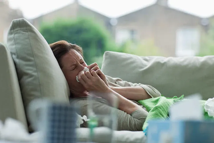 A Women lying on bed suffering from excess mucus