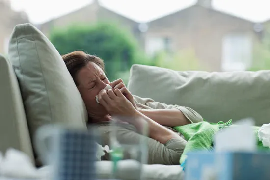 A Women lying on bed suffering from excess mucus