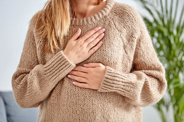 A_woman_holding_her_chest_due_to_chest_congestion.webp