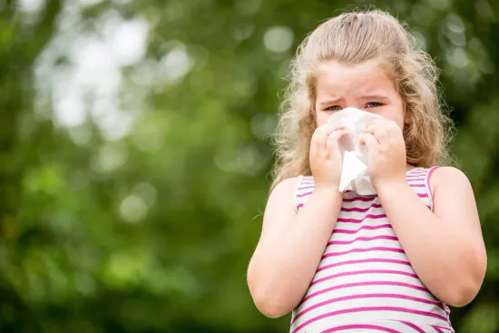 A young girl blowing her nose